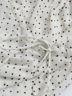 Blouse blanche pour femme col en V manches longues lacées et à volants.