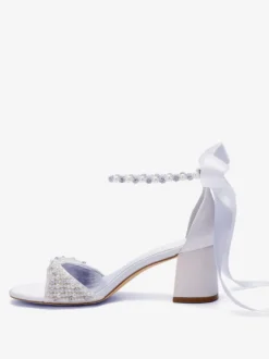 Chaussures de mariée blanches à bout ouvert ornées de perles et de strass avec bride à la cheville et talon compensé.