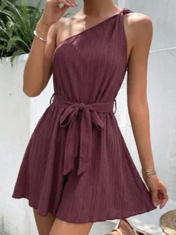 Combinaison-short d'été décontractée pour femme mauve asymétrique avec ceinture et tissu texturé à nouer à la taille.