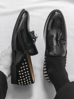 Mocassins noirs à bout rond pour homme ornés de rivets et de pompons.