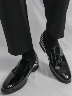 Mocassins noirs à bout rond pour homme ornés de rivets et de pompons.