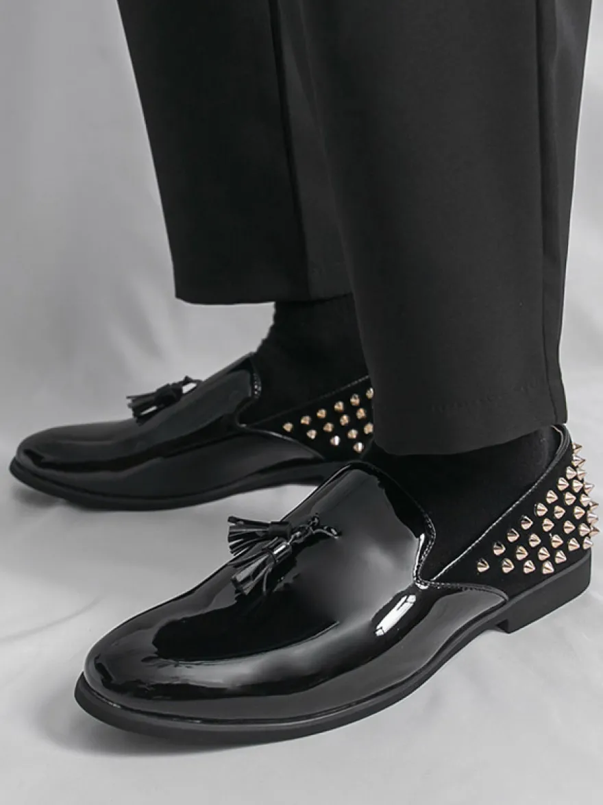 Mocassins noirs à bout rond pour homme ornés de rivets et de pompons.
