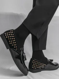 Mocassins noirs à bout rond pour homme ornés de rivets et de pompons.