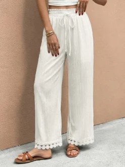 Pantalon large à ourlet en dentelle blanche et cordon de serrage coupe ample et décontractée idéal pour l'été.