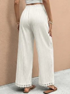 Pantalon large à ourlet en dentelle blanche et cordon de serrage coupe ample et décontractée idéal pour l'été.