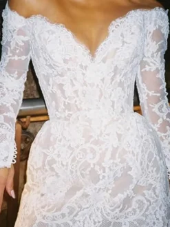 Robe de mariée courte à col en V et manches longues coupe trapèze.