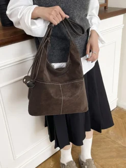Sac hobo vintage en daim avec surpiqûres contrastées bandoulière ajustable et porte-monnaie intégré.