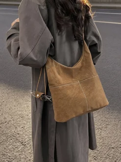 Sac hobo vintage en daim avec surpiqûres contrastées bandoulière ajustable et porte-monnaie intégré.