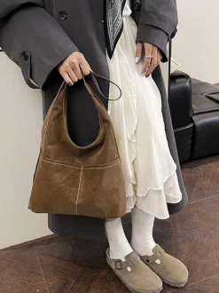 Sac hobo vintage en daim avec surpiqûres contrastées bandoulière ajustable et porte-monnaie intégré.