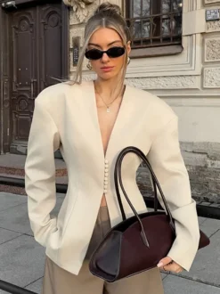 Veste blazer péplum sans manches à col en V et boutonnage nacré à une rangée de boutons.