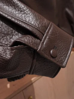 Veste bomber vintage en similicuir noir et marron uni coupe décontractée taille élastiquée.