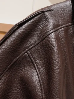 Veste bomber vintage en similicuir noir et marron uni coupe décontractée taille élastiquée.