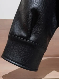 Veste bomber vintage en similicuir noir et marron uni coupe décontractée taille élastiquée.