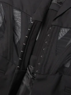 Veste de tailleur cintrée à corset en maille ajourée et dos transparent avec baleines à la taille.